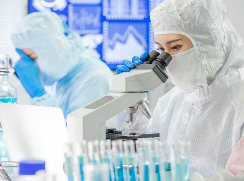 Scientists examining samples under microscopes in a laboratory.
