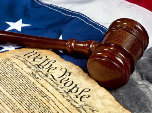 Gavel and Constitution on American flag background.
