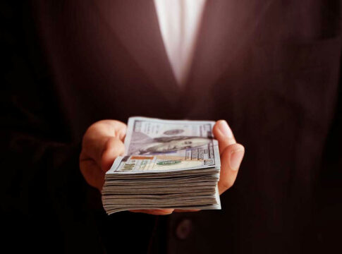 Hand holding a stack of US dollars.