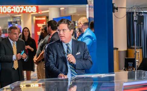 Man in suit speaking at a television studio.