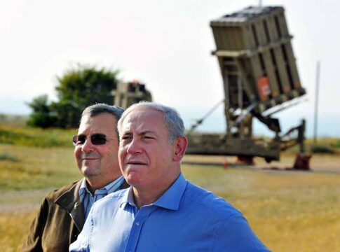 two men standing near a missile defense launcher outdoors