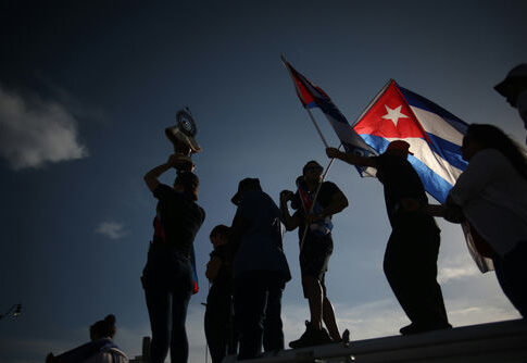 Silhouetted crowd waving Cuban flags at dusk