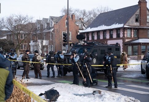 Police officers at a crime scene with a tactical vehicle in a snowy urban area